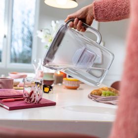 Style Essential White Glas füllen Wasser wird aus dem weißen Style Essential in ein Glas auf einem gedeckten Tisch eingeschenkt.