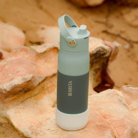 Grüne BRITA LARQ Flasche mit weißem Silikonschutz steht auf einem Stein.