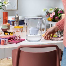 Style Essential White auf Tisch Weiße Kanne auf farbig gedecktem Tisch mit Brille.