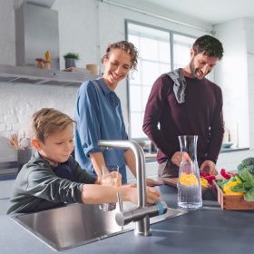 Ein Junge füllt in einer Küche sein Wasserglas mit der BRITA 3 Wege Küchenarmatur auf