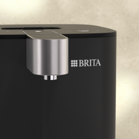 Nahaufnahme des BRITA Cube Wasserspenders von vorne mit Fokus auf den Auslauf und das BRITA Logo.