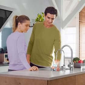 Ein Mann steht neben einer Frau in der Küche und schenkt sich mit BRITA mypure P1 Wasser ein