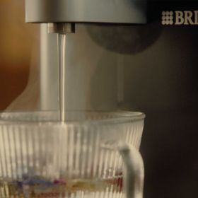 Heißes Wasser läuft in eine Teetasse Nahaufnahme, wie heißes Wasser aus einem Heißwasser-Dispenser in eine gläserne Tasse läuft.