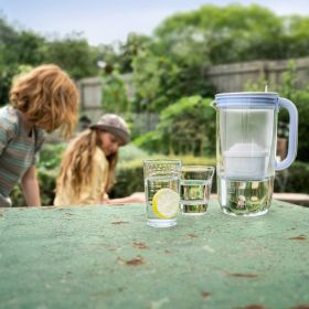 Wasser wird aus einem Tischwasserfilter in Gläser gegossen Wasser wird aus einem Tischwasserfilter in Gläser gegossen