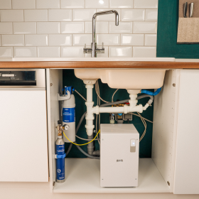 BRITA yource pro select auf der Küchenarbeitsfläche und unter dem Spülbecken sind die Filterkomponenten sichtbar