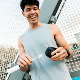 Ein junger Mann im Sportoutfit hält den Deckel und den Filter Straw der BRITA LARQ iQ in der Hand.