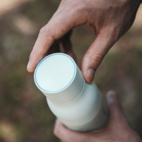 Eine LARQ Bottle Pure Vis wird von zwei Händen gehalten und der Deckel von oben gezeigt.