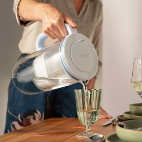 Eine Frau füllt Wasser in ein grünes Glas mit BRITA Tischwasserfilter Glas.
