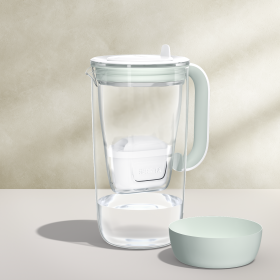 Ein Tischwasserfilter aus Glas in der Farbe Grün, daneben ein passendes Silicone Base