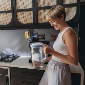 Eine Frau hält den blauen BRITA Tischwasserfilter Glas in einer Küche