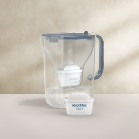 Ein Tischwasserfilter Style XL in der Farbe Stone-Blue mit einem beigefarbenen Hintergrund