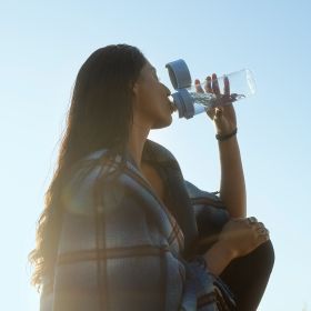 Eine Frau trinkt Wasser aus der BRITA Wasserfilterflasche Model Vital