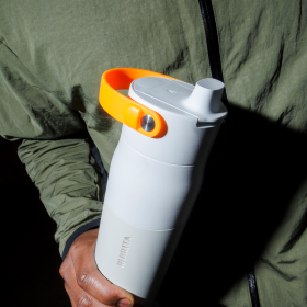 Eine weiße BRITA LARQ Wasserfilterflasche mit orangenem Griffband