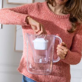 Frau setzt MAXTRA PRO Filter in weiße Kanne ein.