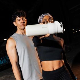Zwei sportliche Personen posieren im urbanen Setting, eine hält eine weiße BRITA LARQ Filterflasche