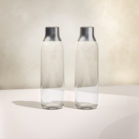Zwei BRITA sodaTRIO Flaschen aus Glas beiger Hintergrund Zwei BRITA sodaTRIO Flaschen aus Glas nebeneinander mit beigem Hintergrund
