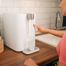 Frau bedient den BRITA yource pro top auf der Küchenarbeitsfläche, während ein Glas mit frischem Wasser befüllt wird
