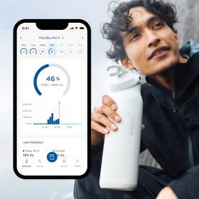 Ein junger Mann trinkt an einer BRITA LARQ Flasche, daneben ein Handy mit BRITA LARQ App.