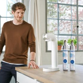 Ein Mann steht in der Küche neben einem weißen BRITA sodaONE und zwei CO2 Zylindern