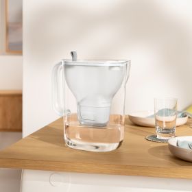 Tischwasserfilter Style steht auf Tisch Der Tischwasserfilter Style in Blau steht auf einem gedeckten Holztisch.