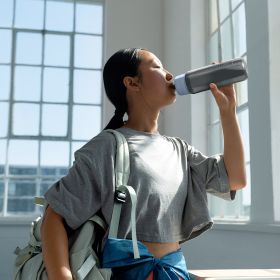 Eine Frau trinkt Wasser aus der BRITA Wasserfilterflasche Model Active