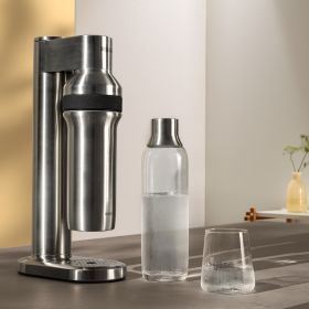 BRITA sodaTRIO pro Wassersprudler steht neben einer Glasflasche und einem Glas Wasser. 