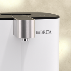 Nahaufnahme des BRITA Cube Wasserspenders von vorne mit Fokus auf den Auslauf und das BRITA Logo.