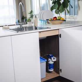 Ein eingebauter P1000 Filter in einer braunen Küche unter der Spüle von der BRITA 3 Wege Küchenarmatur 