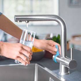 Eine Frau füllt in einer Küche Ihr Wasserglas mit der BRITA 3 Wege Küchenarmatur auf