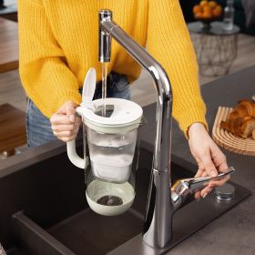 Ein grüner Tischwasserfilter Glas wird in einer Küche am Wasserhahn befüllt