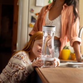 Ein Mädchen schaut sich die BRITA Wasserkaraffe mit Filter an in einer Küche an.