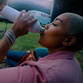 Frau trinkt aus sodaTRIO Edelstahlflasche Frau trinkt aus sodaTRIO der kleinen sodaTRIO Edelstahlflasche in Weiß.